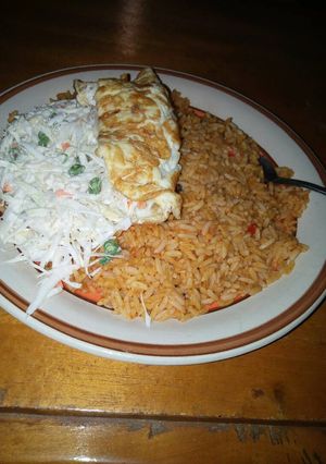A picture of Jollof rice,vegetable salad and fried egg.