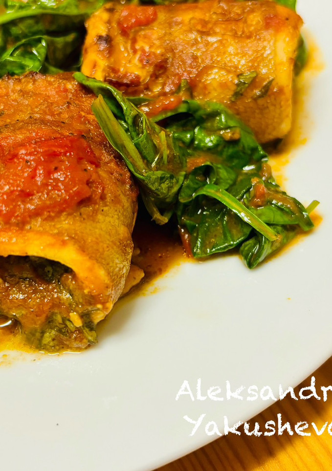 A picture of Cod rolls with tomatoes and spinach.