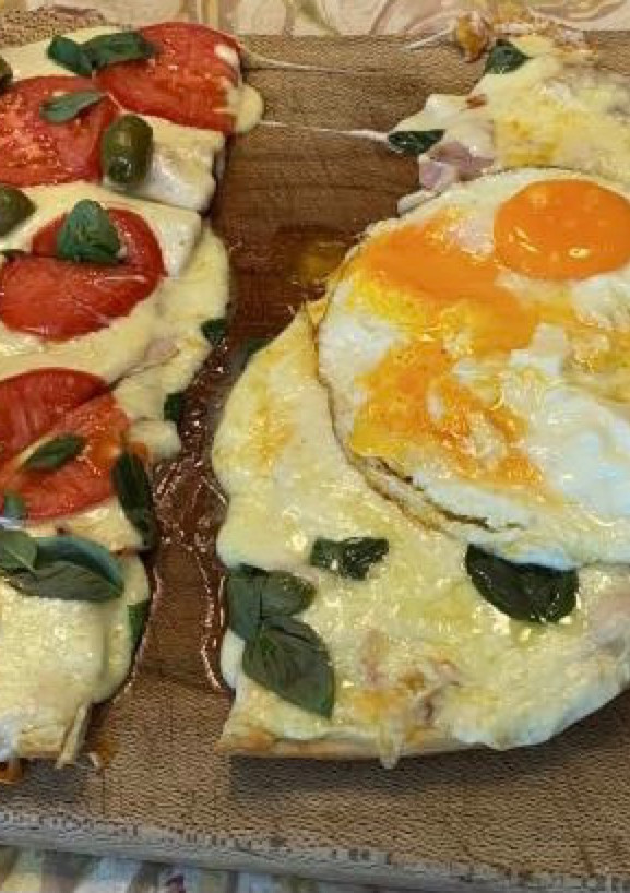 Una foto de Pizza a la piedra 1/2 Napolitana y 1/2 panceta y huevos fritos