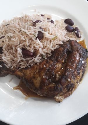 A picture of Jerk chickens with pea rice.