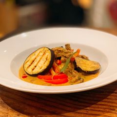 A picture of Beef and grilled aubergine red curry topped with Bird eye chillis.