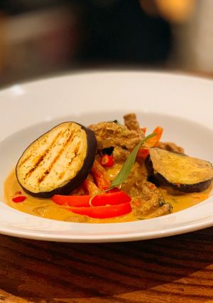 A picture of Beef and grilled aubergine red curry topped with Bird eye chillis.