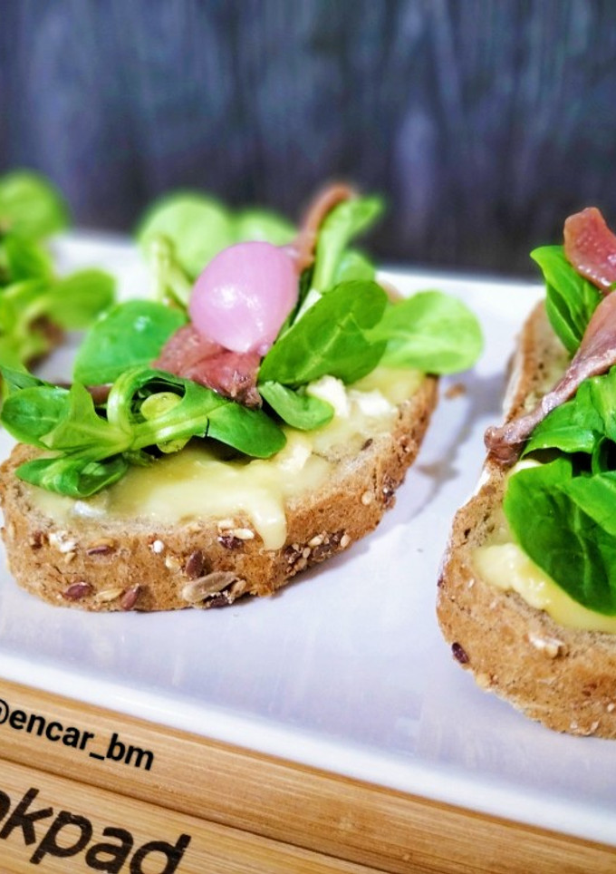 Una foto de Tosta de camembert, canónigos y anchoas