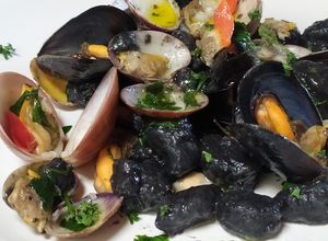 Foto di Gnocchi al nero di seppia con molluschi,prezzemolo e aglio