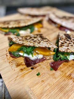 Una foto de Quesadilla de melocotón, jamón, queso de cabra y rúcula