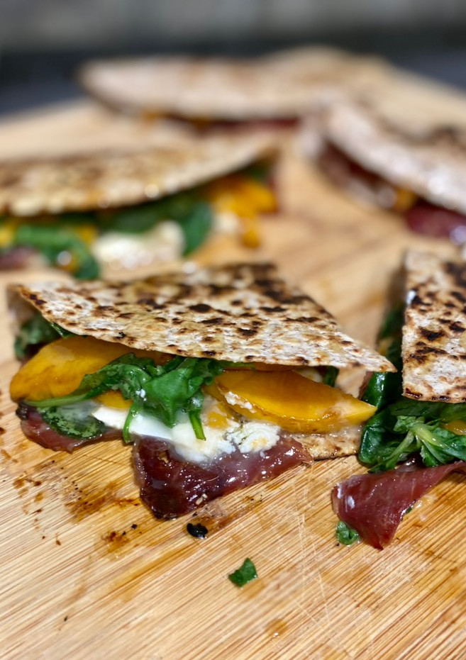 Una foto de Quesadilla de melocotón, jamón, queso de cabra y rúcula
