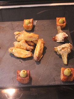 Una foto de Alitas y alcachofas fritas con vasitos de patatas bravas