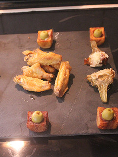 Una foto de Alitas y alcachofas fritas con vasitos de patatas bravas