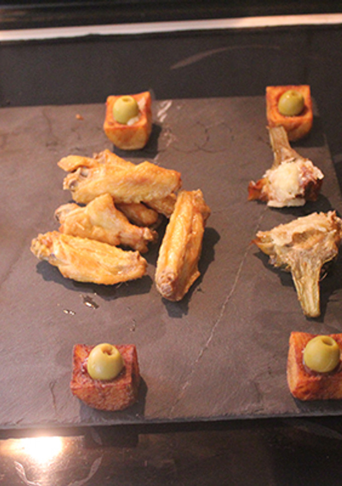 Una foto de Alitas y alcachofas fritas con vasitos de patatas bravas