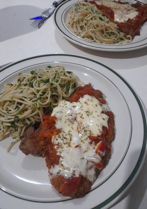 Una foto de Milanesa napolitana con fideos al pesto