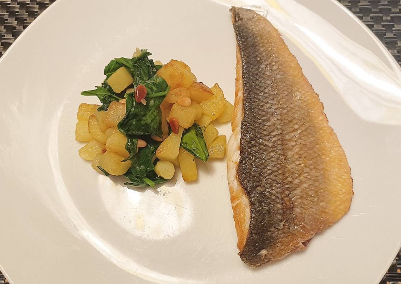 Pan fried sea bass with potatoes, spinach and toasted pine nuts