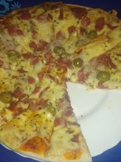 Una foto de Pizza de jamón serrano, salchichas y aceitunas