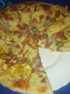 Una foto de Pizza de jamón serrano, salchichas y aceitunas