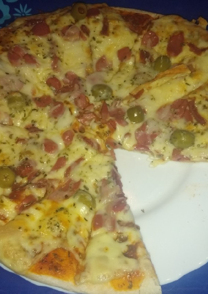 Una foto de Pizza de jamón serrano, salchichas y aceitunas