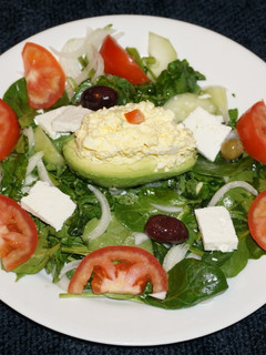 Una foto de PALTA RELLENA CON ENSALADA DE HUEVO SOBRE UNA CAMA DE ESPINACA CON BERROS. JON STYLE