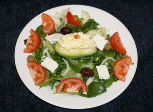 Una foto de PALTA RELLENA CON ENSALADA DE HUEVO SOBRE UNA CAMA DE ESPINACA CON BERROS. JON STYLE