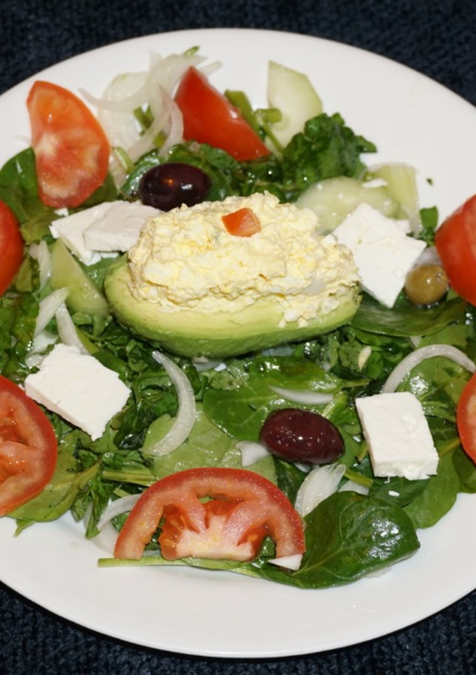 Una foto de PALTA RELLENA CON ENSALADA DE HUEVO SOBRE UNA CAMA DE ESPINACA CON BERROS. JON STYLE