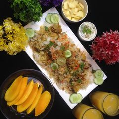 A picture of ChatpatiBombay biryani with tang twist, yogurt salad, mango, apple cubes.