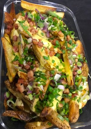 Una foto de Papas cheddar con panceta y verdeo