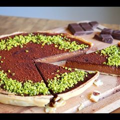 A picture of Rich, dark chocolate tart with pistachio crumb.