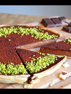 A picture of Rich, dark chocolate tart with pistachio crumb.