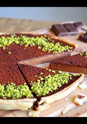 A picture of Rich, dark chocolate tart with pistachio crumb.