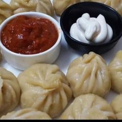 A picture of Delicious Momos with red chutney.