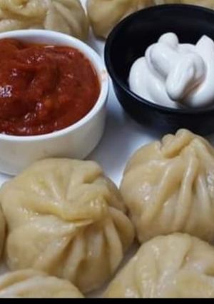 A picture of Delicious Momos with red chutney.