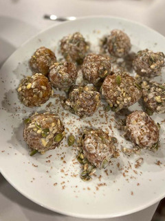 Una foto de Croquetas de queso cabra y dátiles envueltas en leche de coco, semillas y chocolate