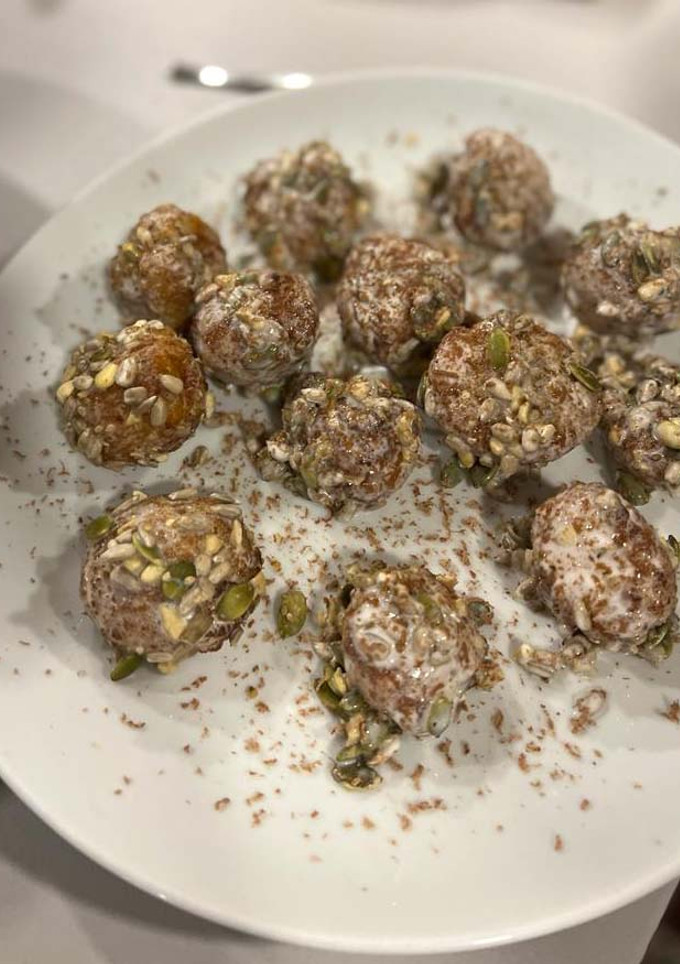 Una foto de Croquetas de queso cabra y dátiles envueltas en leche de coco, semillas y chocolate