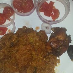 A picture of Garnished jellof rice with chicken.