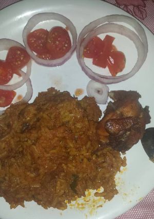 A picture of Garnished jellof rice with chicken.