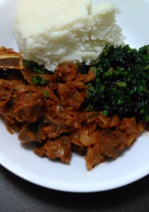 A picture of Ugali served with boiled mutton and spinach.
