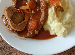Una foto de Ossobuco en salsa de tomate con puré de papas