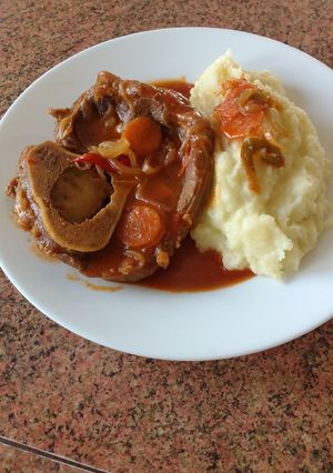 Una foto de Ossobuco en salsa de tomate con puré de papas