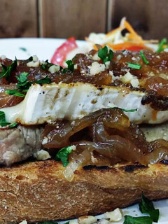 Una foto de Tosta de solomillo ibérico con queso brie, cebolla caramelizada y crujientes de nueces