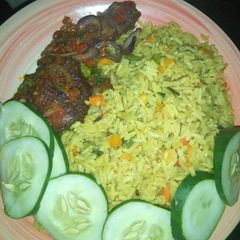 A picture of Fried rice with peppered chicken dressed with cucumber.