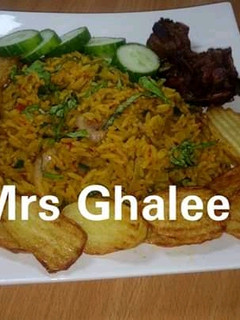 A picture of Jallof rice with chips and fry meat.