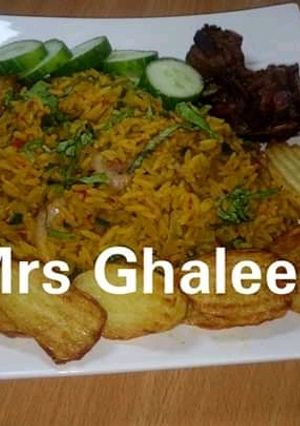 A picture of Jallof rice with chips and fry meat.
