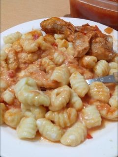 Una foto de Ñoquis de papa acompañado de salsa de tomate con pollo