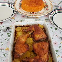 A picture of Red rice with chicken legs and potatoes.