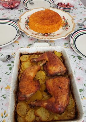 A picture of Red rice with chicken legs and potatoes.