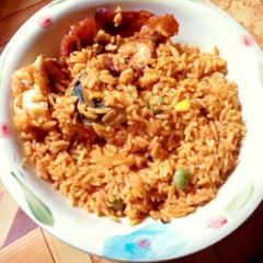 A picture of Jollof rice with fried plantain and fish.
