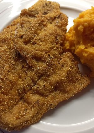 Una foto de Milanesa de pescadilla apanada con polenta