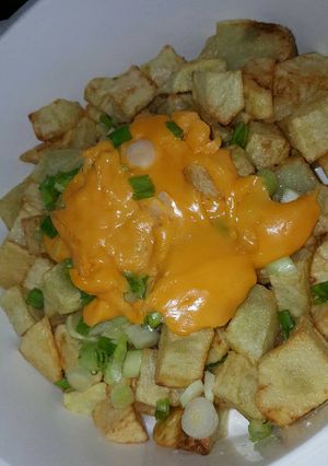 Una foto de Papas fritas con cheddar y cebollita de verdeo