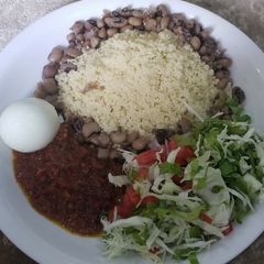 A picture of Cooked couscous and beans with sauce and vegetables.