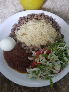 A picture of Cooked couscous and beans with sauce and vegetables.