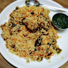 A picture of Chicken biryani with green coriander chutney.