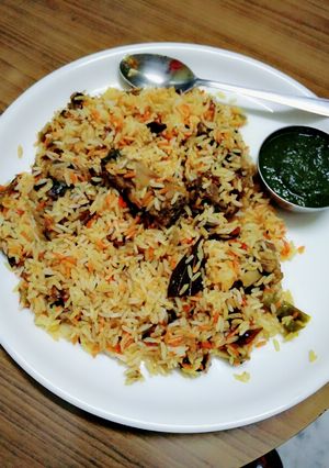 A picture of Chicken biryani with green coriander chutney.