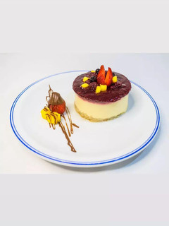 Una foto de Cheesecake de mango, con salsa de frambuesa y arándanos 🥭